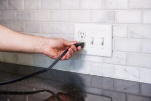 Hand plugging appliance into electrical outlet.