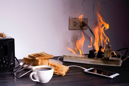 Electrical outlet caught on fire that spread to power strip and surrounding area.